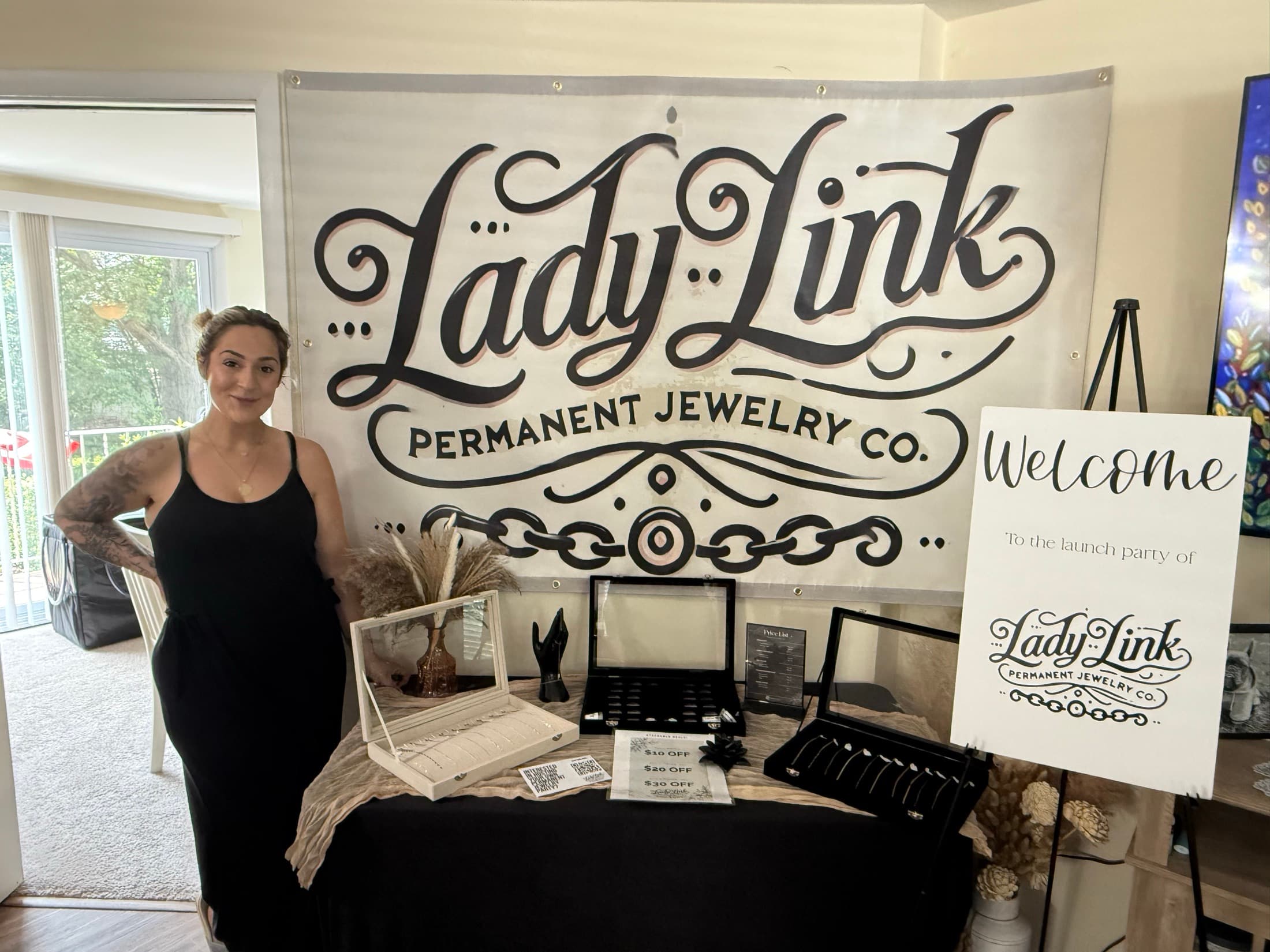 Jenna beside the Lady Link banner and jewelry display at her launch party